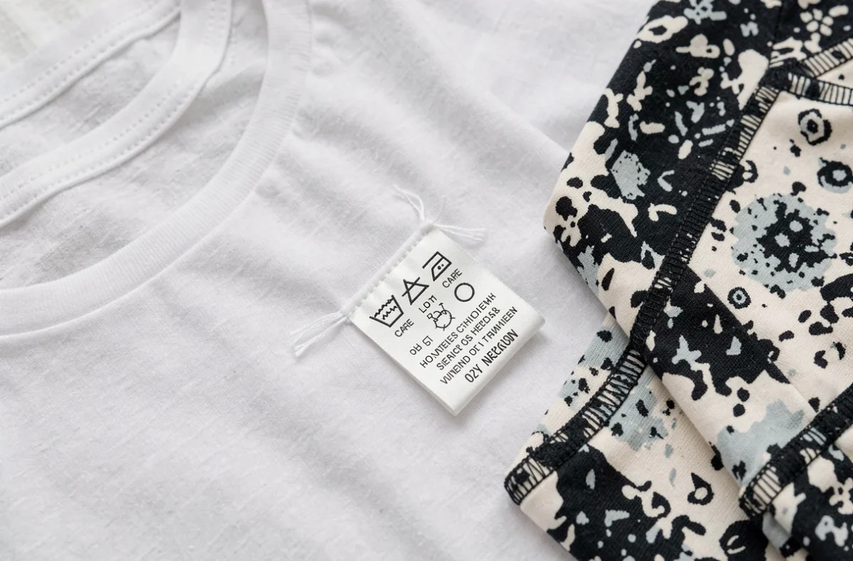 Vue rapprochée de vêtements synthétiques bon marché avec étiquettes d'entretien révélant leur composition chimique